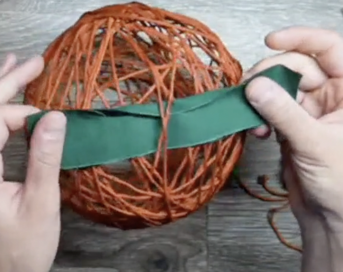 cut fabric/ribbon strip for leaf on top and tie to one of the yarn pieces on pumpkin